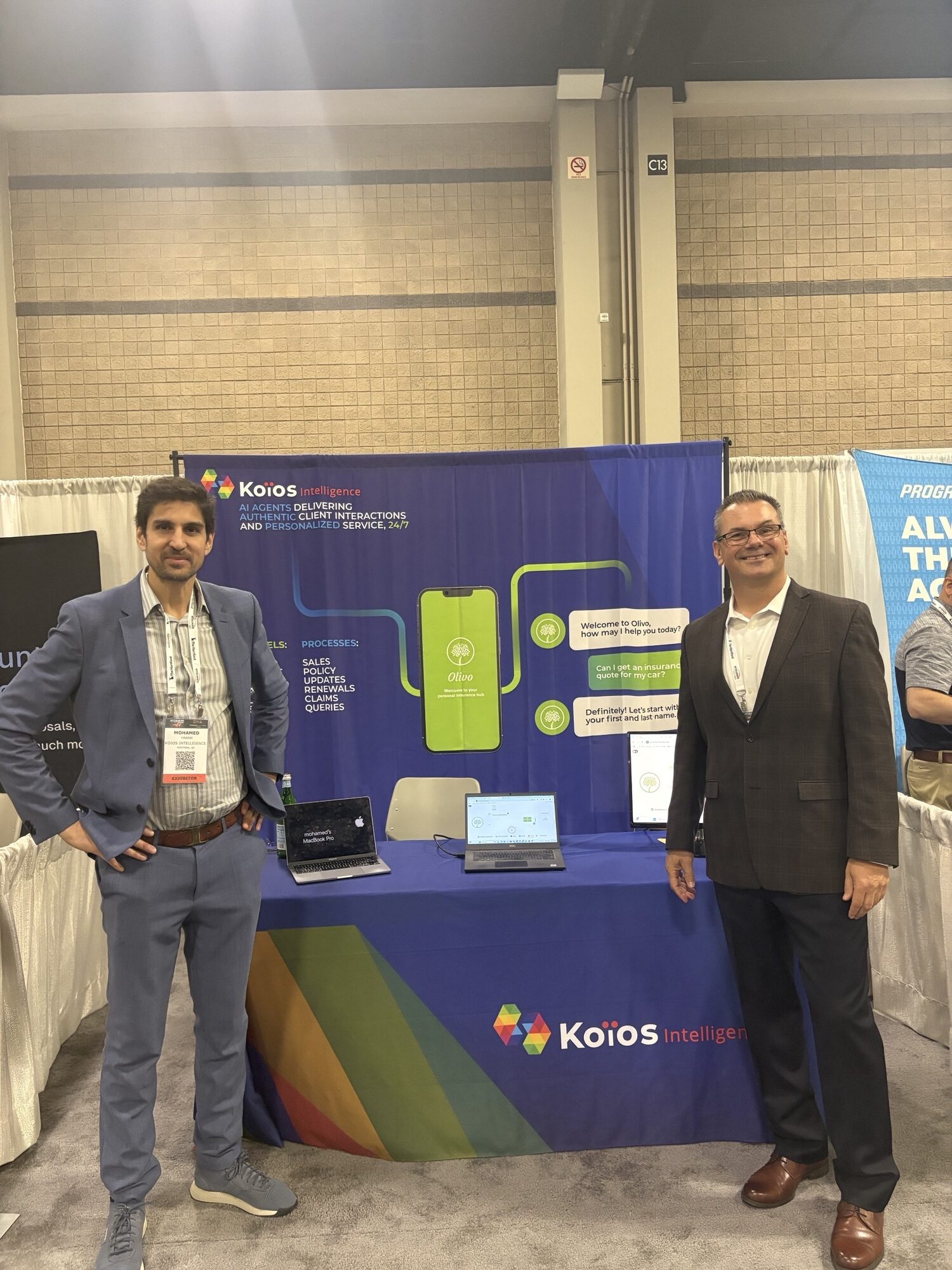 IMG_5908 CEO and SVP Insurance & AI Transformation in front of a Koios Intelligence convention booth.